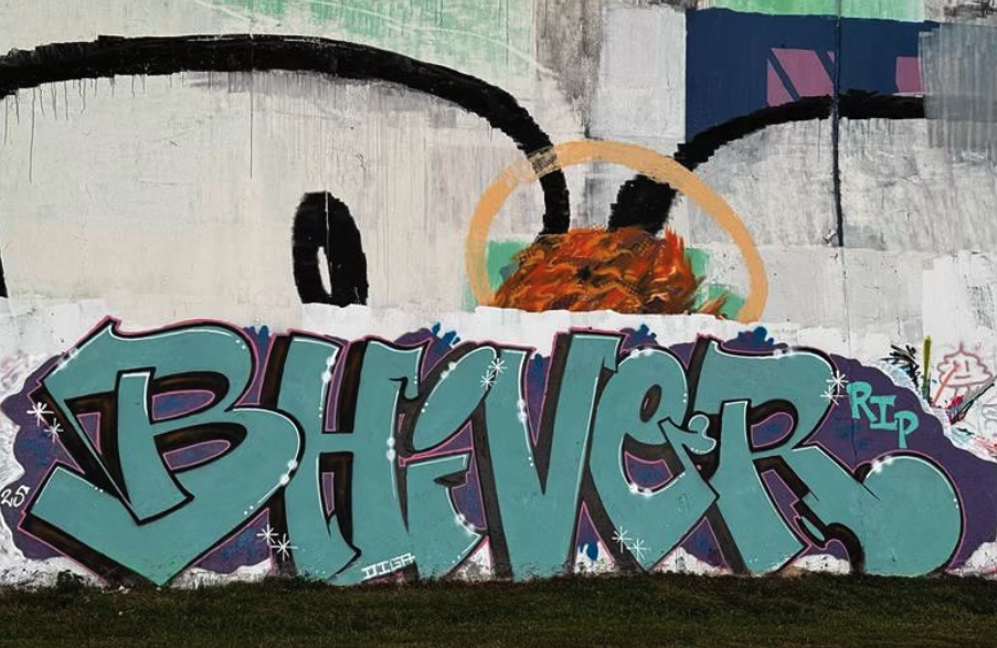 Graffiti mural reading “BHIVER” in bold teal and purple lettering with “RIP” painted beside it, set against a large wall featuring abstract shapes and a haloed figure